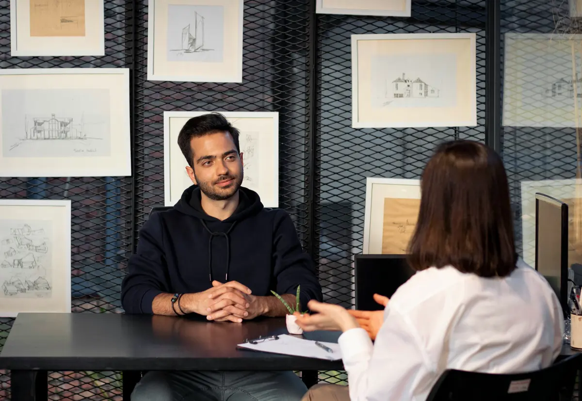 A candidate in an interview facing a recruiter, in an office with sketch-covered walls