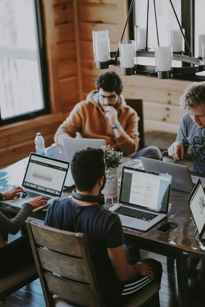 A team working together on laptops around a table, in a warm and collaborative atmosphere